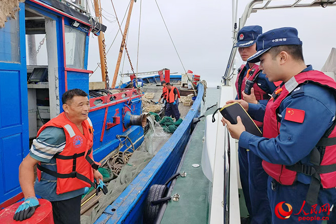 山东烟台海警局长岛工作站执法员在辖区海域登检作业渔船。刘鑫 摄